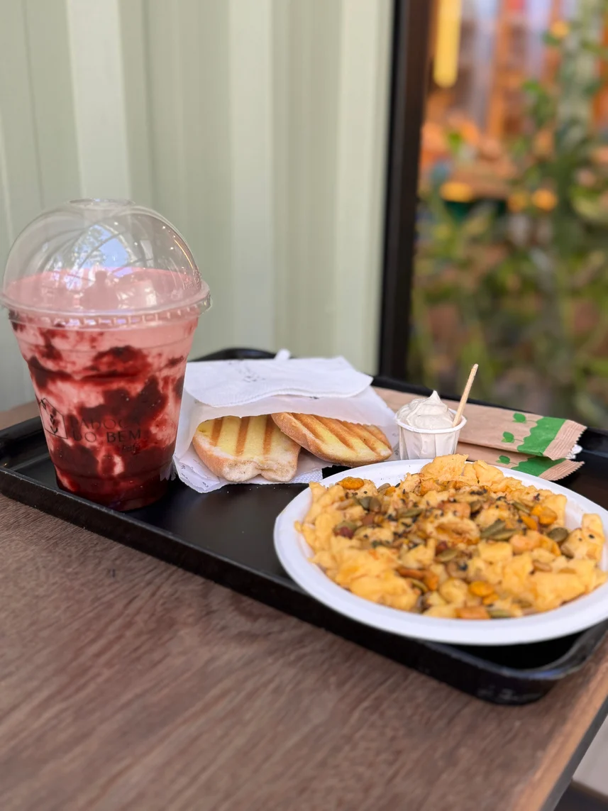 Brunch da Padoca Café com bebida de frutas vermelhas, ovos mexidos e pão servido à mesa