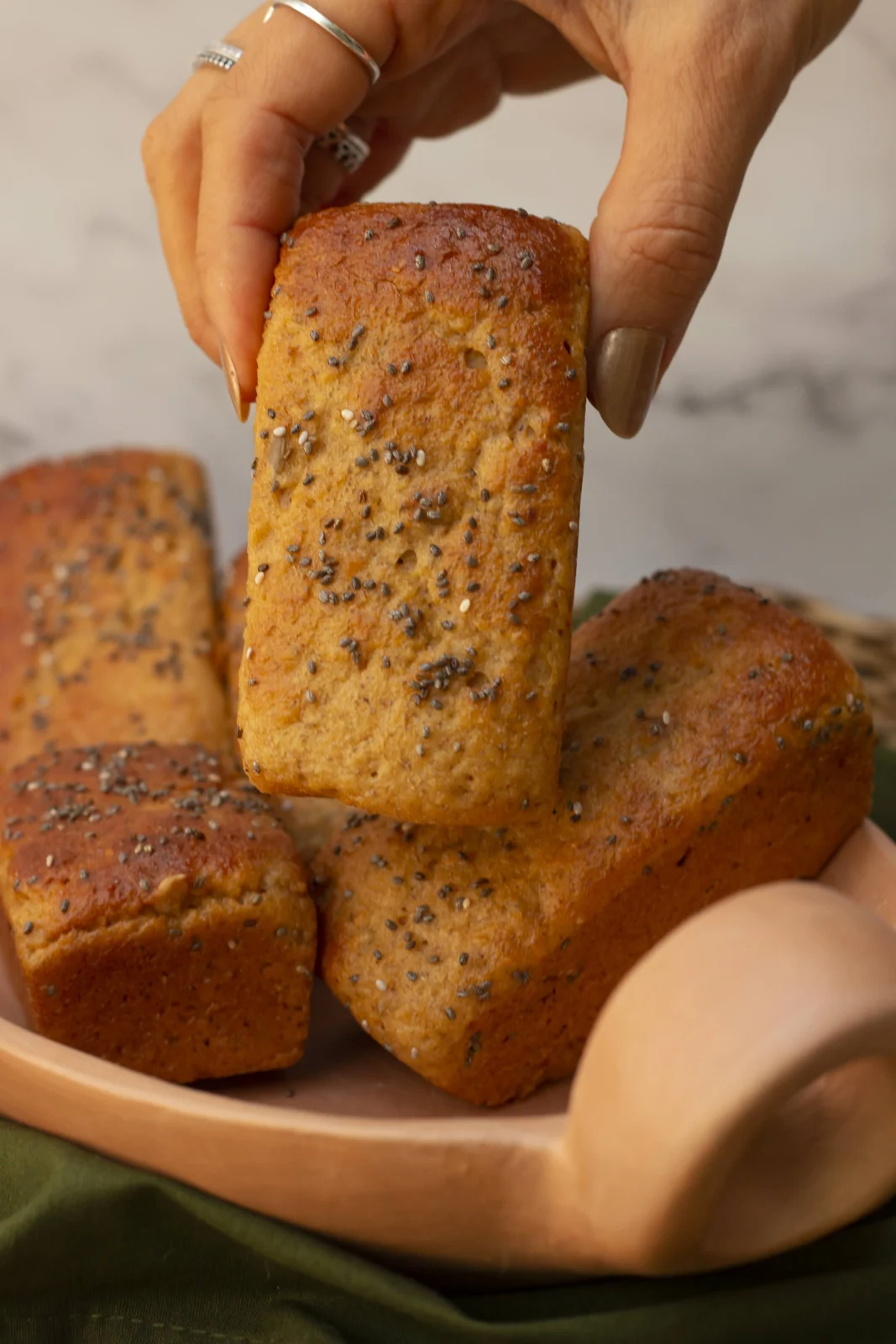 Pão artesanal da Padoca do Bem cortado em fatias, segurado com as mãos